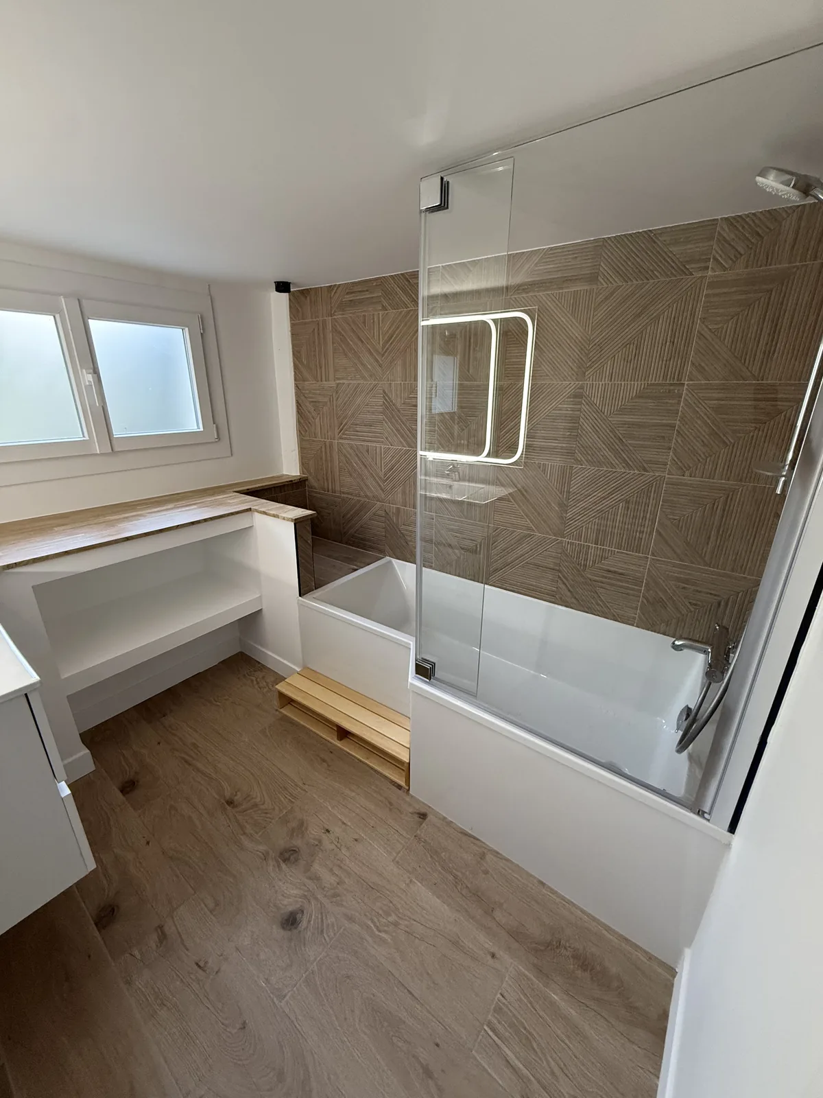 Baignoire avec pare-bain vitré et faïence effet bois après rénovation à Galluis (78)