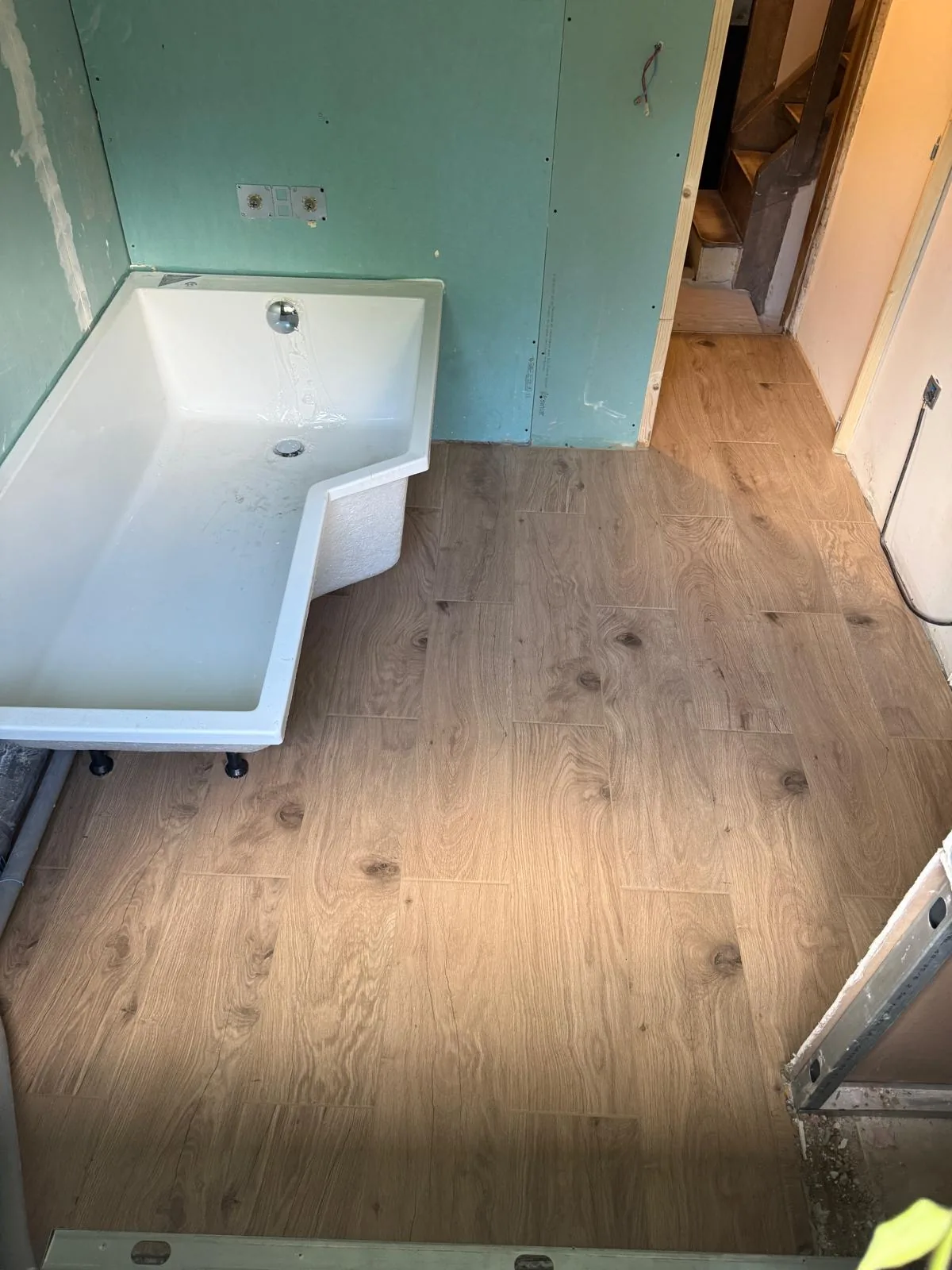 Nouvelles cloisons en plaques de plâtre hydrofuges et baignoire posée sur le carrelage imitation bois à Galluis