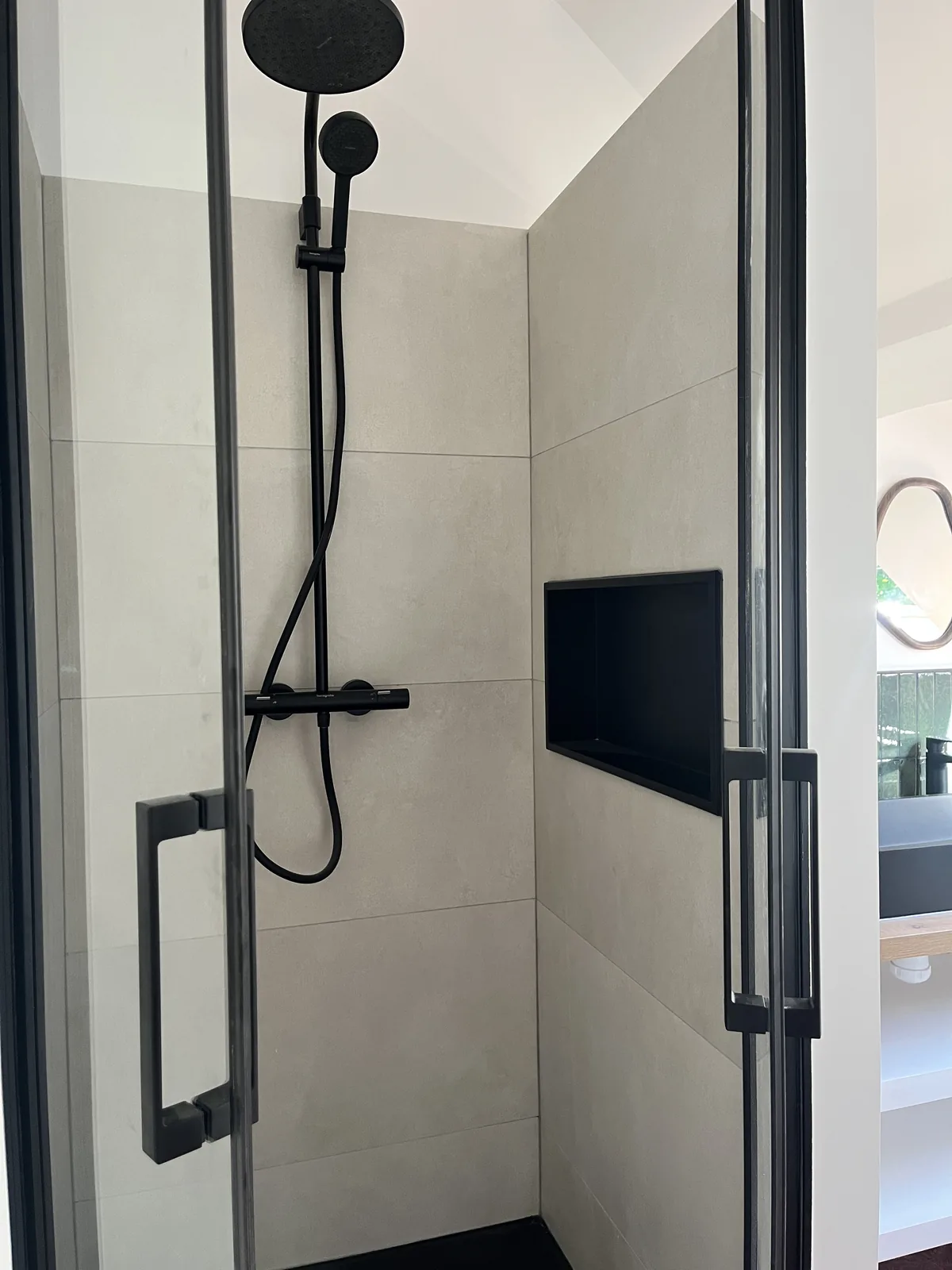 Douche à l’italienne avec niche encastrée, colonne de douche noire et paroi vitrée après rénovation à Grosrouvre