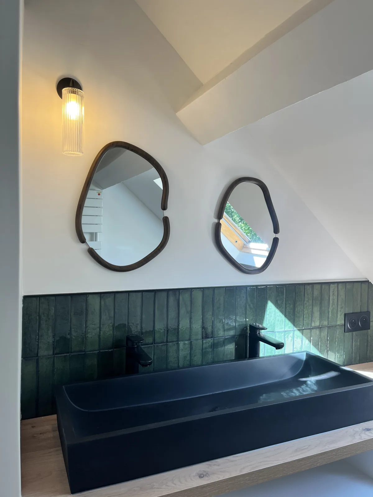 Vasque noire sur plan bois, crédence verte et miroirs organiques après rénovation à Grosrouvre