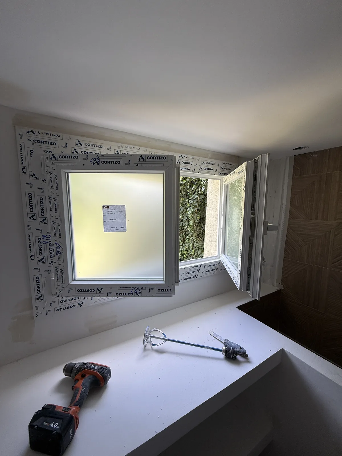 Fenêtre neuve posée en rénovation, film de protection encore en place, salle de bain à Galluis