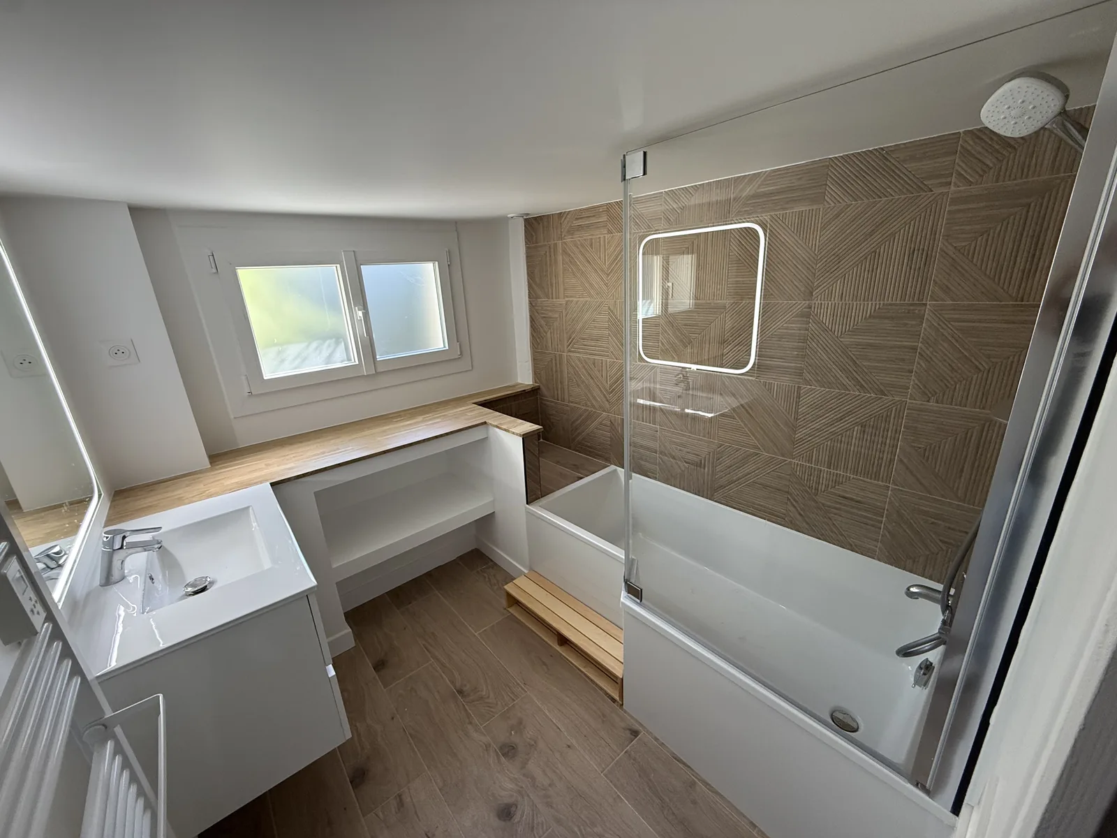 Rénovation complète d’une salle de bain à Galluis (78) : baignoire avec pare-bain, faïence effet bois et fenêtre neuve, par ABRP