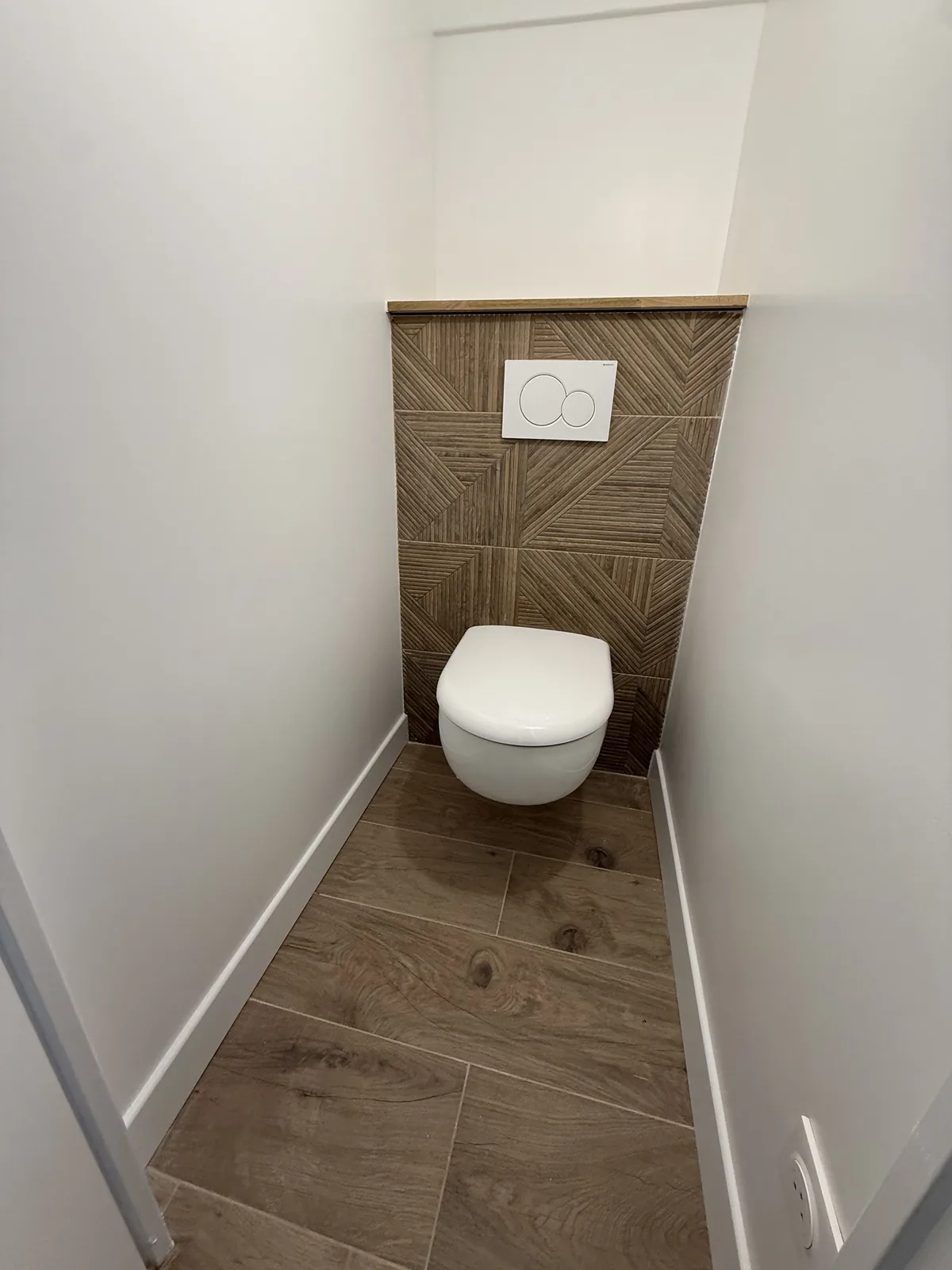 WC suspendu Geberit dans son espace séparé, habillé de faïence effet bois, après travaux à Galluis